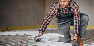 Service man instelling house heating system under the floor