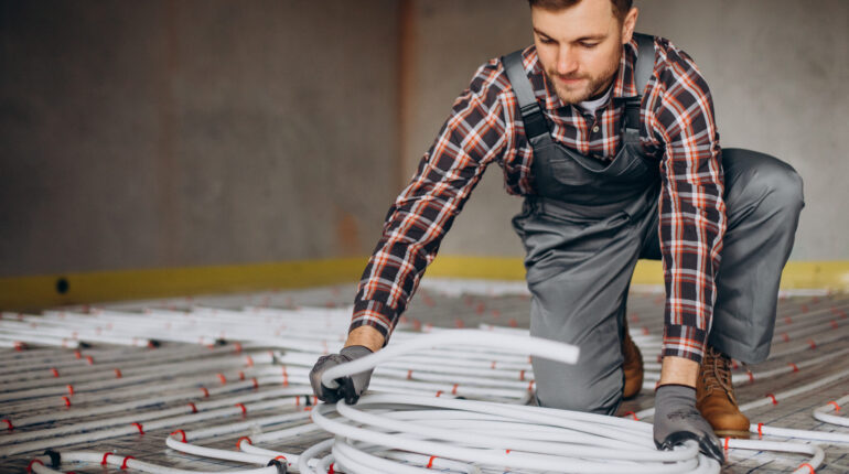 Service man instelling house heating system under the floor